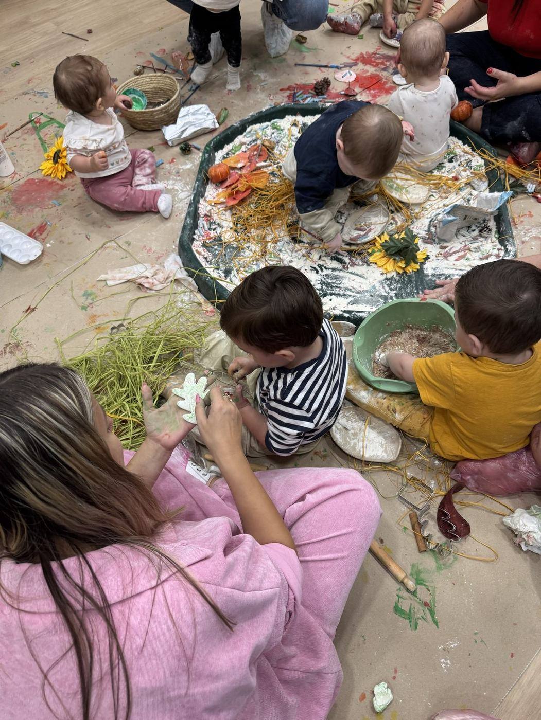 Μωρά παίζουν με φθινοπωρινό sensory tray με αλεύρι και άχυρο σε παιδικό πάρτι