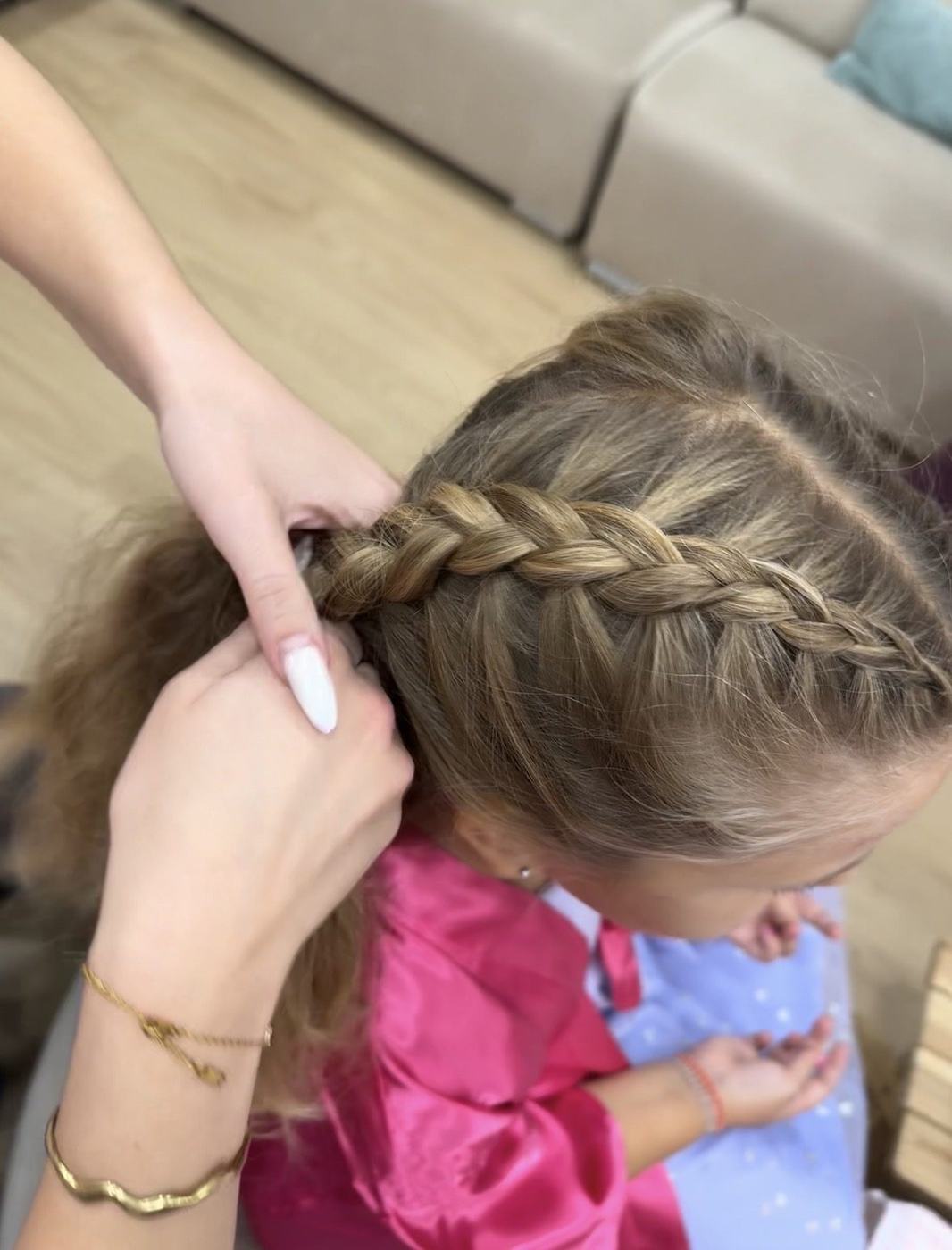 Πλεξούδα σε παιδί με ροζ σατέν ρόμπα στο hair bar του spa party