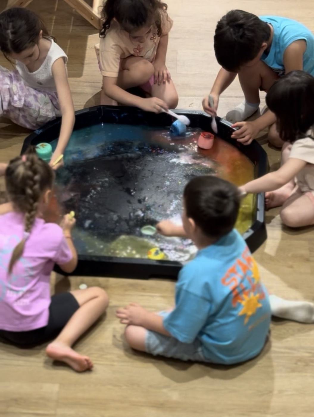 Παιδιά μαζεμένα γύρω από sensory tray σε παιδικό πάρτι
